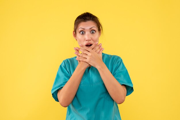Medico femminile di vista frontale in camicia medica sul covid dell'ospedale del virus di salute di colore dell'infermiera medica dello scrittorio giallo