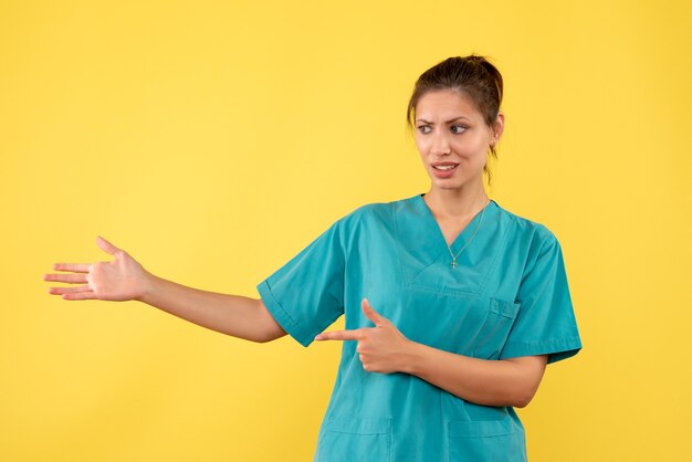Medico femminile di vista frontale in camicia medica sul virus covid dell'ospedale del medico di salute dell'infermiere del pavimento giallo