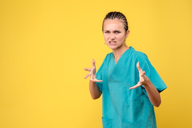 Medico femminile di vista frontale in camicia medica sull'ospedale dell'infermiera di colore del virus covid-19 di emozione di salute dello scrittorio giallo