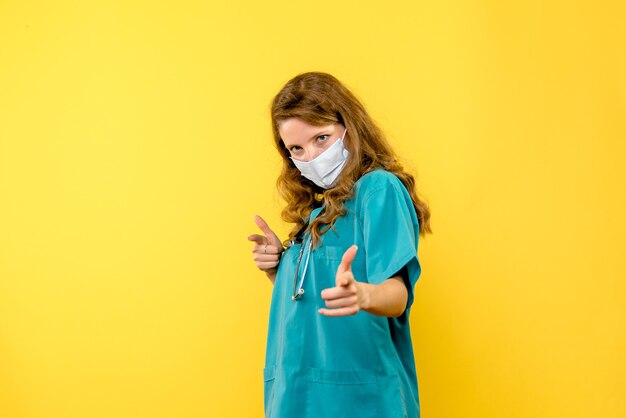 Medico femminile di vista frontale in maschera sullo spazio giallo