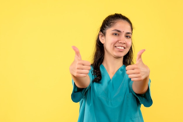 Medico femminile di vista frontale in uniforme che fa pollice sul segno in piedi