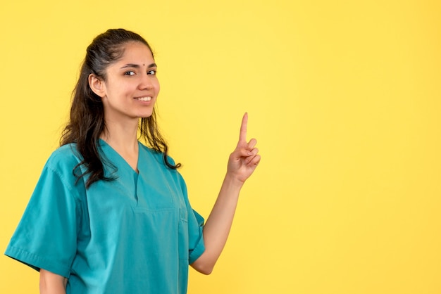 Medico femminile di vista frontale in uniforme che indica alla condizione del soffitto