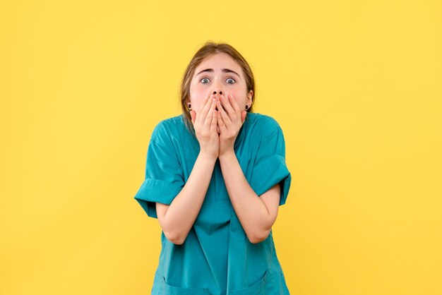 Medico femminile di vista frontale scioccato sul medico dell'ospedale di salute di emozione del fondo giallo