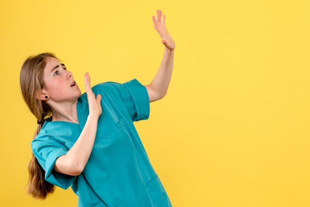 Medico femminile di vista frontale spaventato di qualcosa sull'emozione dell'ospedale del medico di salute del fondo giallo