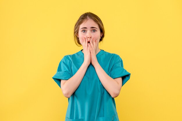 Medico femminile di vista frontale spaventato sul medico di salute dell'ospedale di emozione sfondo giallo