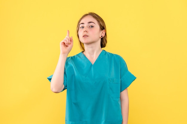 Medico femminile di vista frontale sul medico dell'ospedale di emozione di salute del fondo giallo