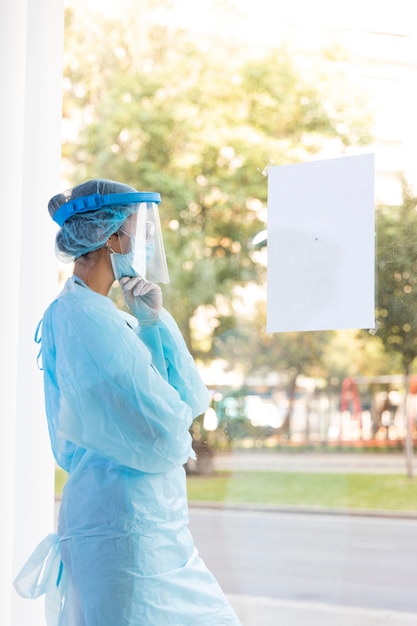 Medico femminile di vista laterale che osserva fuori dalla finestra