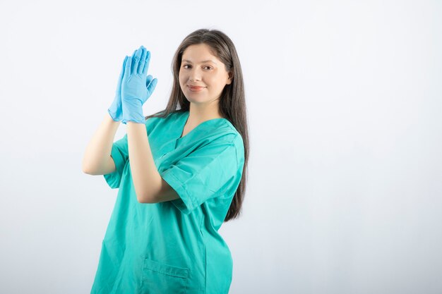 Medico femminile in guanti medici che mostrano le mani su bianco.