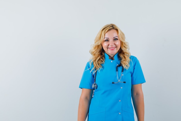 Medico femminile in uniforme blu che sorride e che osserva lo spazio felice per testo