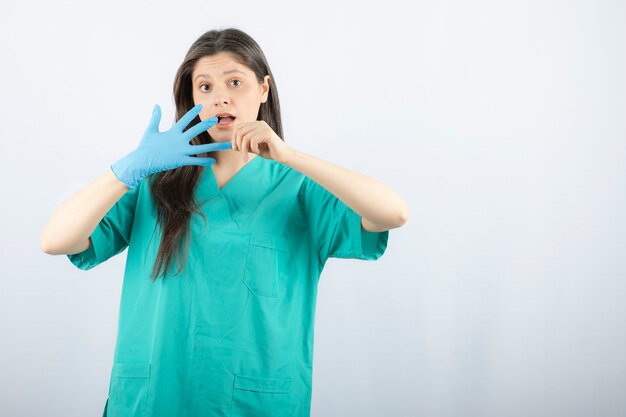 Medico femminile in uniforme che si toglie il guanto medico.