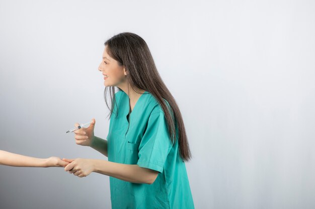 Medico femminile in uniforme verde che ottiene sparato su bianco.