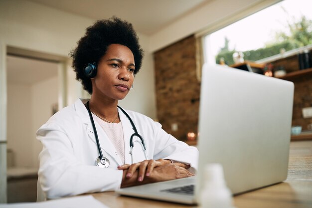 Medico femminile nero che ha una teleconferenza sul computer portatile