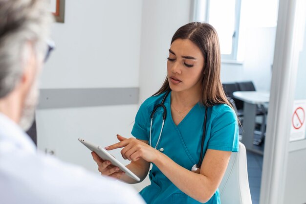 Medico femminile rassicurante che sostiene il paziente adulto anziano in ospedale Gentile giovane donna infermiera o badante che aiuta l'uomo pensionato più anziano che parla dando conforto esprimendo il concetto di cura