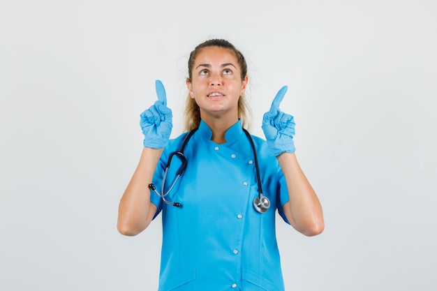 Medico femminile rivolto verso l'alto le dita in uniforme blu