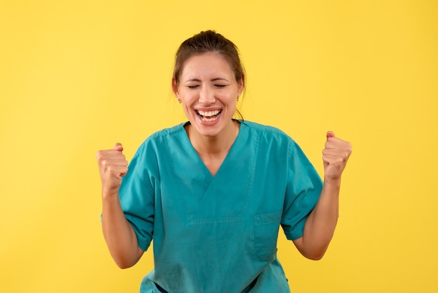 Medico femminile vista frontale in camicia medica che si rallegra su sfondo giallo