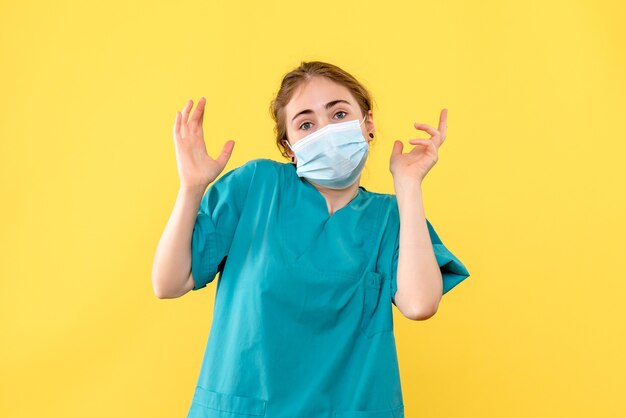 Medico femminile vista frontale in maschera su sfondo giallo virus della salute pandemia covid