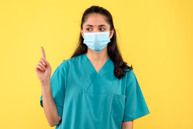 Medico femminile vista frontale in uniforme alzando la mano in piedi