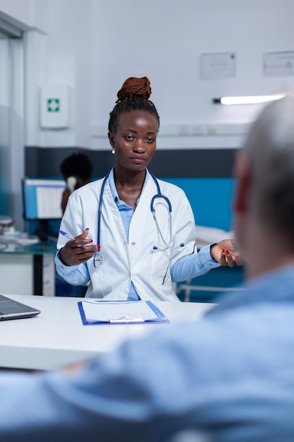 Medico generico che discute con un pensionato malato sugli effetti collaterali della medicina prescritta. Esperto medico che spiega i sintomi della malattia e i risultati della diagnosi al paziente anziano malato