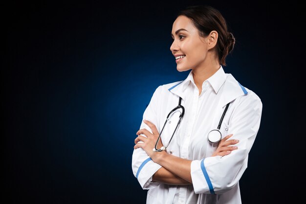 Medico grazioso della donna del brunette che osserva da parte e che sorride