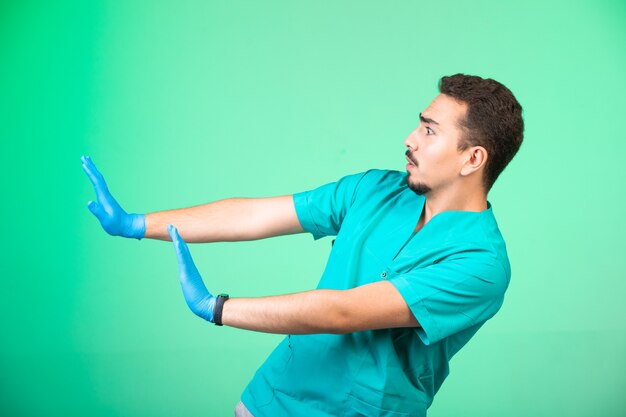 Medico in uniforme e maschera per le mani che si impedisce sul verde.