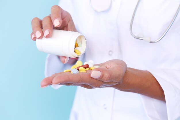 Medico indossa veste bianca e stetoscopio tenendo le pillole