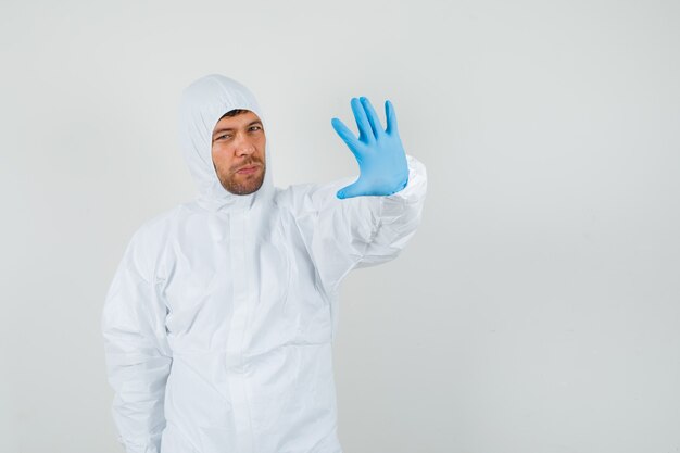 Medico maschio che mostra il gesto di rifiuto in tuta protettiva, vista frontale guanti.