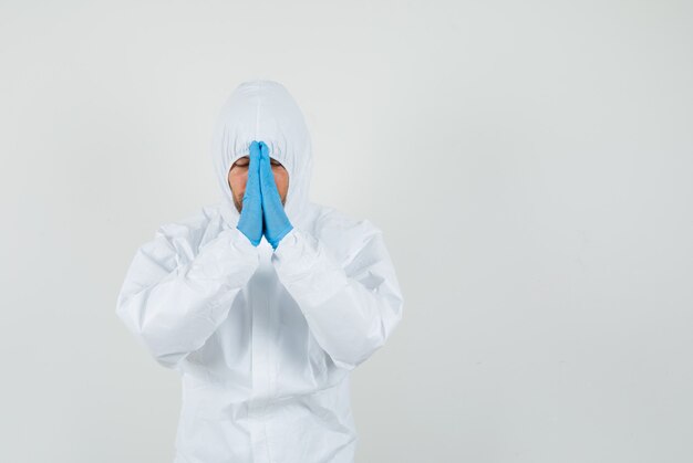 Medico maschio che tengono le mani nel gesto di preghiera in tuta protettiva