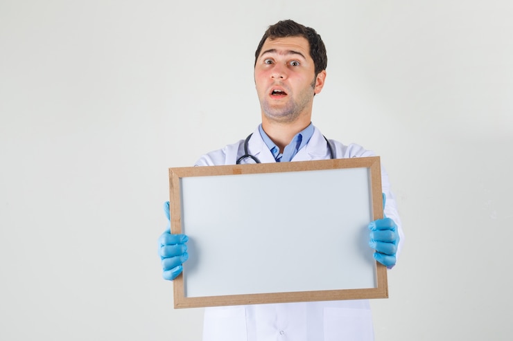 Foto gratuito medico maschio che tiene scheda bianca in camice bianco, guanti e guardando scioccato, vista frontale.