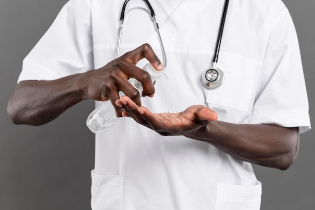 Medico maschio che usando disinfettante per le mani per la sua sicurezza