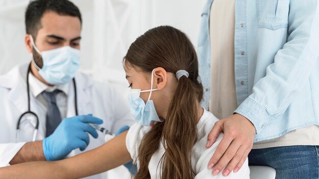 Medico maschio che vaccina una ragazza