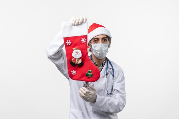 Medico maschio di vista frontale che tiene il calzino di festa sulla salute del virus di Natale di covid dello scrittorio bianco