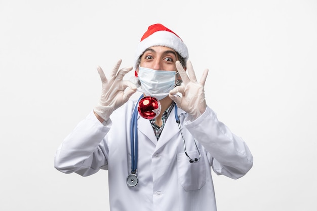 Medico maschio di vista frontale che tiene il virus covid di salute del giocattolo dell'albero del nuovo anno