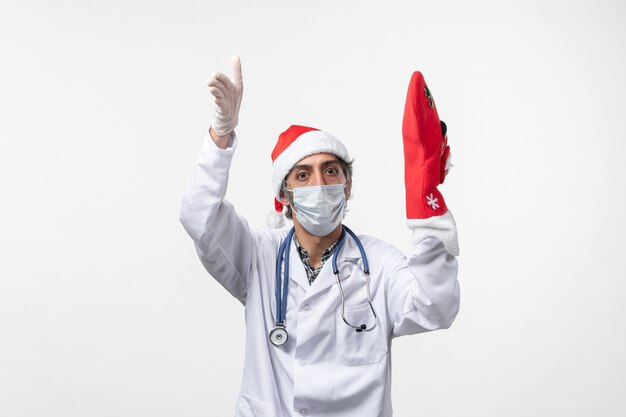 Medico maschio di vista frontale con grande calzino rosso sulla vacanza di Natale covid virus muro bianco