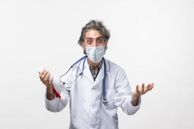 Medico maschio di vista frontale con la maschera sulla pandemia di virus covid del nuovo anno della parete bianca