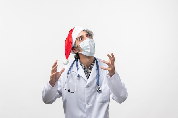 Medico maschio di vista frontale con maschera sterile sul nuovo anno pandemico del virus covid della parete bianca