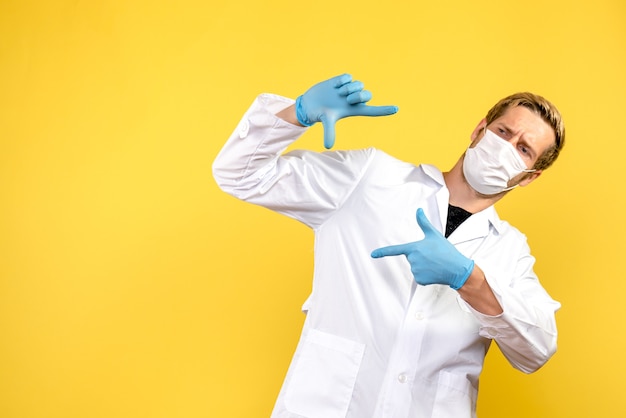 Medico maschio di vista frontale nella foto che cattura posa sulla pandemia di virus covid di salute del fondo giallo