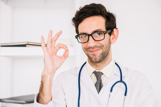 Medico maschio felice che gesturing segno giusto