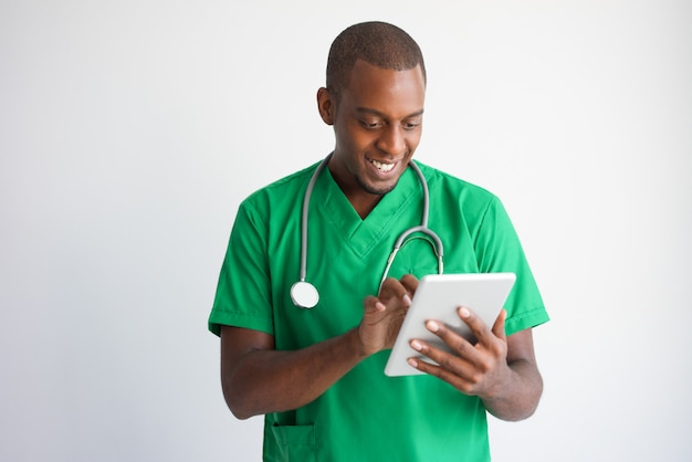 Medico maschio nero sorridente che per mezzo del calcolatore del ridurre in pani. Tecnologia nel concetto di medicina.