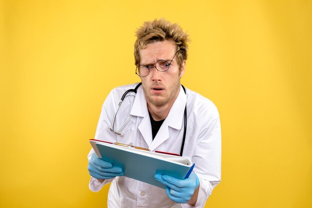 Medico maschio vista frontale con analisi su sfondo giallo medico covid-salute umana