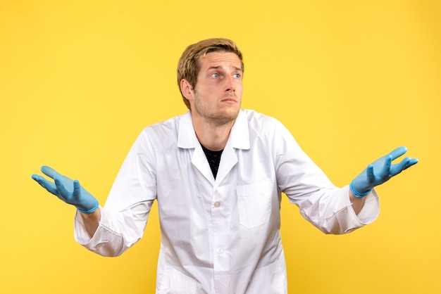 Medico maschio vista frontale con la faccia confusa su sfondo giallo covid-emozione medica umana
