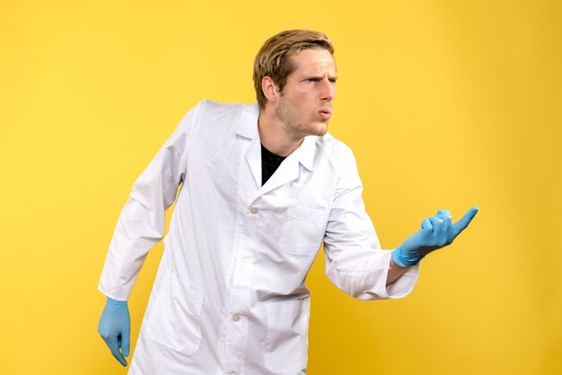 Medico maschio vista frontale confuso su sfondo giallo covid-ospedale medico umano