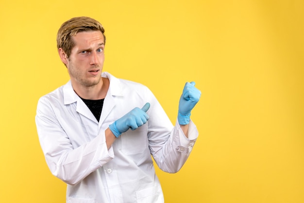 Medico maschio vista frontale confuso su uno sfondo giallo covid-medico ospedale umano