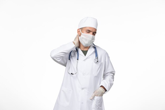 Medico maschio vista frontale in tuta medica e indossa una maschera contro covid sulla pandemia di medicina virus covid parete leggera