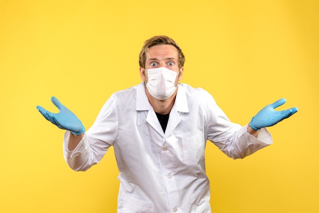 Medico maschio vista frontale sorpreso su sfondo giallo medico salute covid pandemia