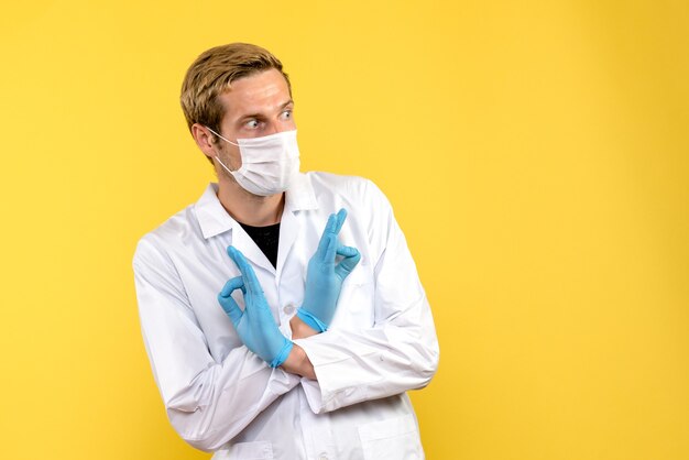 Medico maschio vista frontale spaventato su sfondo giallo virus della pandemia covid-salute