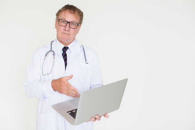 Medico maturo serio che indica al computer portatile
