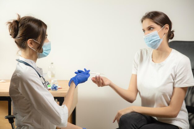 Medico o infermiere che somministra il vaccino al paziente utilizzando la siringa iniettata in ospedale. Preparazione della dose nell'ago. Protezione contro coronavirus, pandemia COVID-19 e polmonite. Sanità, medicina.