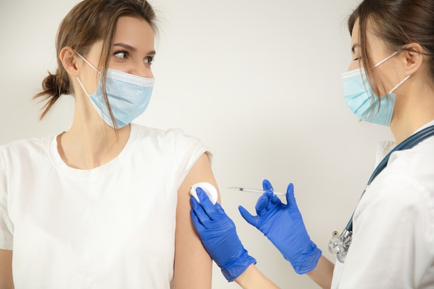 Medico o infermiere che somministrano il vaccino al paziente utilizzando la siringa iniettata in ospedale. Preparazione della dose nell'ago. Protezione contro coronavirus, pandemia COVID-19 e polmonite. Assistenza sanitaria, medicina.