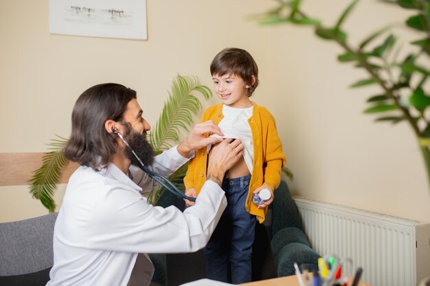 Medico pediatra che esamina un bambino in uno studio medico confortevole