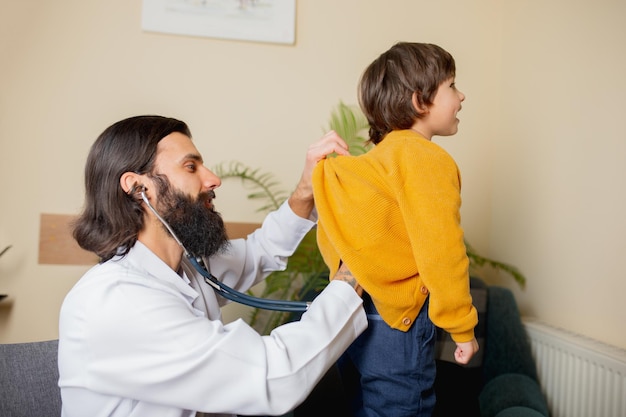 Medico pediatra che esamina un bambino in uno studio medico confortevole